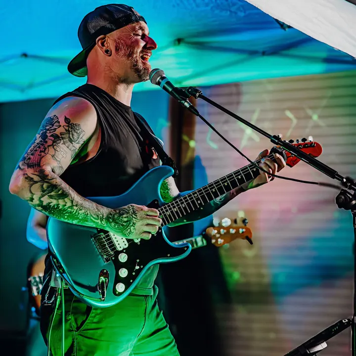 Tim Apple singing and playing guitar on stage